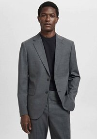 Costume gris cintré avec un blazer structuré et un pantalon assorti. Comprend deux boutons à l'avant, des revers crantés et un sous-vêtement noir texturé.