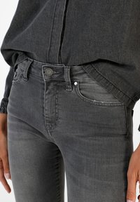 Dark gray jeans made of denim, featuring a classic five-pocket design, belt loops, and a button closure with a subtle distressed detail.