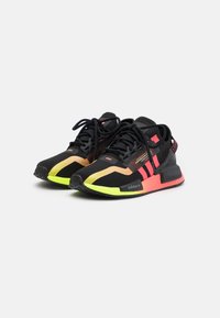Black athletic shoes with mesh upper, neon accents in pink and yellow, textured sole, and three signature stripes in red.