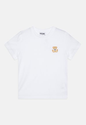 Hvid t-shirt med korte ærmer med en lille brun teddybjørn, der holder et "Toy" skilt på venstre brystområde og rund halsudskæring.