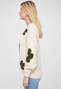 Knit sweater in cream with dark green floral patterns. Features drop sleeves, relaxed fit, and ribbed cuffs and hem.