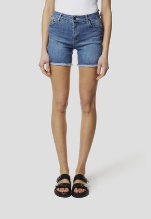 Svetlomodré rifľové šortky s ošúchaným lemom, s priliehavým strihom a klasickým päťvreckovým dizajnom. Doplnene čiernymi sandálmi s dvoma prackami.