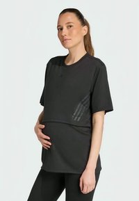 Melnā grūtniecības T-kreklā ar īsām piedurknēm, viegla auduma, apaļa kakla izgriezums un horizontāla paneļa dizains papildu komfortam. Smalka logo un akcenti.