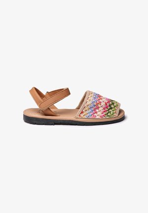 Sandalias tejidas con parte superior de tela beige con acentos multicolores, correa ajustable de cuero marrón y suela de goma negra texturizada.