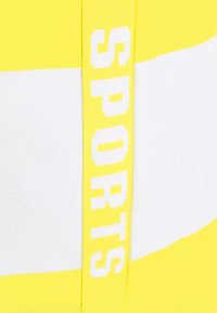 Keltainen ja valkoinen urheilumallinen tanktop, jossa on rohkea keltainen "SPORTS" -teksti sivulla. Toppi on valmistettu pehmeästä, teksturoidusta kankaasta ja siinä on urheilullinen muotoilu.