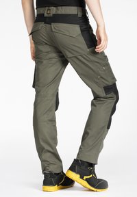 Pantalons de travail en vert olive, dotés d'une ceinture noire, de poches multiples et de coutures contrastées. Conçus pour la durabilité et l'utilité.