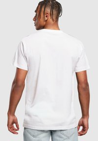 Hvid bomulds t-shirt med korte ærmer og rund halsudskæring, med et enkelt design og en afslappet pasform, vist fra bagsiden.