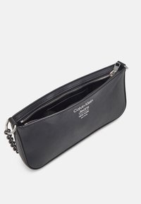 Černé kožené psaníčko se zipovým zapínáním, s potiskem loga a stříbrným zipem. Hladká textura a elegantní design.