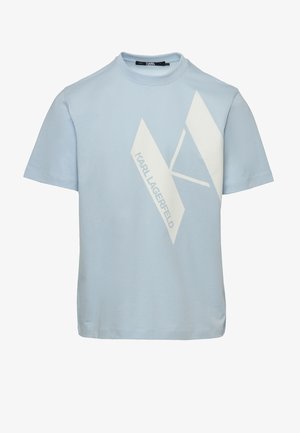 Vaaleansininen puuvillainen t-paita, jossa valkoinen graafinen logo, yhdistetty tummiin kuviollisiin housuihin ja valkoisiin lenkkareihin. Yksinkertainen, nykyaikainen malli.