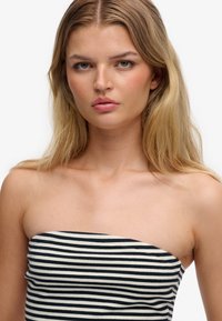 Haut bustier à rayures horizontales bleu marine et crème, présentant une coupe ajustée et un tissu en coton doux. Texture lisse, sans matériel visible.