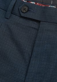 Dark navy suit trousers with subtle light blue windowpane pattern and a black button at the waistband, showing partial interior patterned lining.