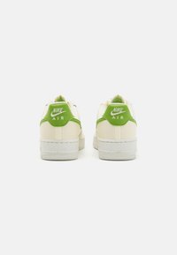 Nike Air tenisice sa kremastom gornjom delom i zelenim naglaskom na peti, teksturisanom gumenom potplatom i belim šavovima.