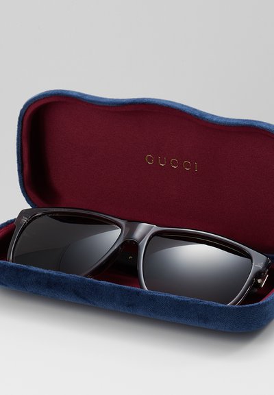 Sluneční brýle Gucci v námořnickém sametovém pouzdře s burgundským interiérem. Sluneční brýle mají tmavé čočky a lesklý černý rám.