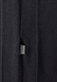 Černá pletená tkanina s hladkým povrchem a viditelným štítkem značky přišitém na boku.