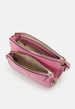 Sac bandoulière rose à double fermeture éclair avec des garnitures en or, présentant deux compartiments ouverts doublés de tissu beige imprimé au nom de la marque.
