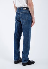 Jeans in denim blu leggero con una vestibilità rilassata, caratterizzati da gamba dritta, due tasche posteriori e un'etichetta nera del brand sulla vita.