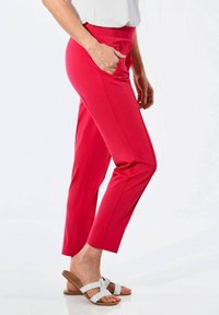 Pinke Hosen mit schlankem Schnitt, ausgestattet mit einem breiten elastischen Bund und seitlichen Taschen. Glattes Material mit einem eleganten, modernen Design.