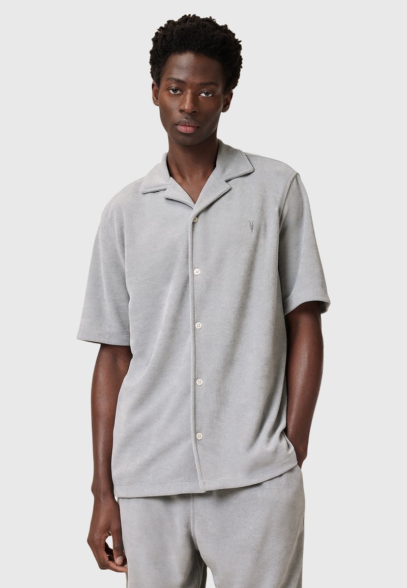 Camicia grigia chiaro a maniche corte realizzata in morbido tessuto spugna, con colletto a punte, chiusura frontale con bottoni e logo ricamato in modo sottile sul petto.