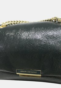 Borsa a mano nera con texture, dotata di tracolla in catena dorata e dettaglio con placca. Presenta una finitura stropicciata, una forma elegante e un accento con logo.