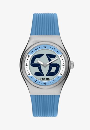Round silver watch with blue silicone strap, blue and white dial, stylized "56" design, and "Fossil" branding, showing 10:10 time.