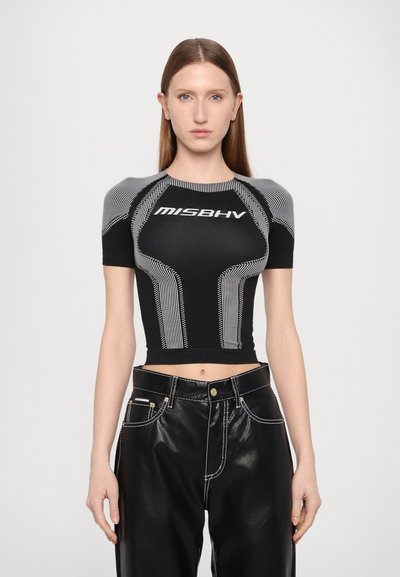 Tricou scurt, negru, cu logo alb "MISBHV" și detalii în dungi; design ajustat cu mâneci scurte, asociat cu pantaloni negri cu talie înaltă.