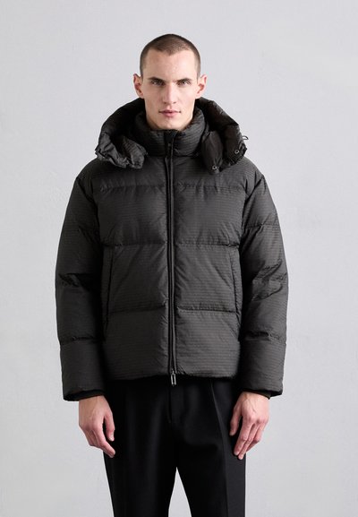 Giubbotto imbottito nero con superficie texturizzata, dotato di colletto alto, chiusura con zip e cappuccio ampio. Realizzato in materiale isolante.