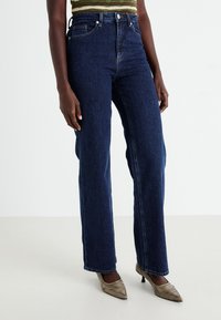 High-waisted dark blue jeans made of denim, featuring a straight leg design and classic five-pocket styling.