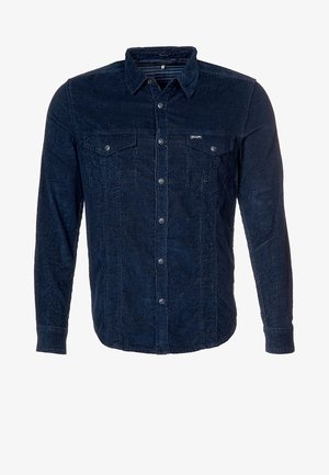 Camisa de pana azul oscuro de manga larga con botones, dos bolsillos en el pecho y cuello, mostrada sobre un fondo blanco.