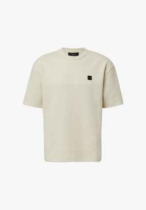 Cremefarbener Baumwoll-T-Shirt mit kurzen Ärmeln, rundem Halsausschnitt und einem kleinen schwarzen Logopatch auf der Brust. Minimalistisches Design.
