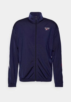 Marineblauw Reebok trainingsjack met volledige ritssluiting aan de voorkant, hoge kraag, elastische manchetten en Reebok-logo op de linkerborst.