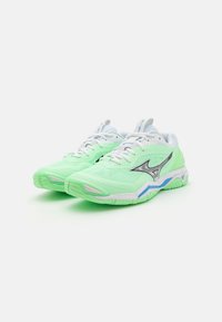 Baskets de sport vert clair avec une tige en mesh, accents blancs et un logo noir. Présentent une surface texturée et un design de semelle rembourrée.