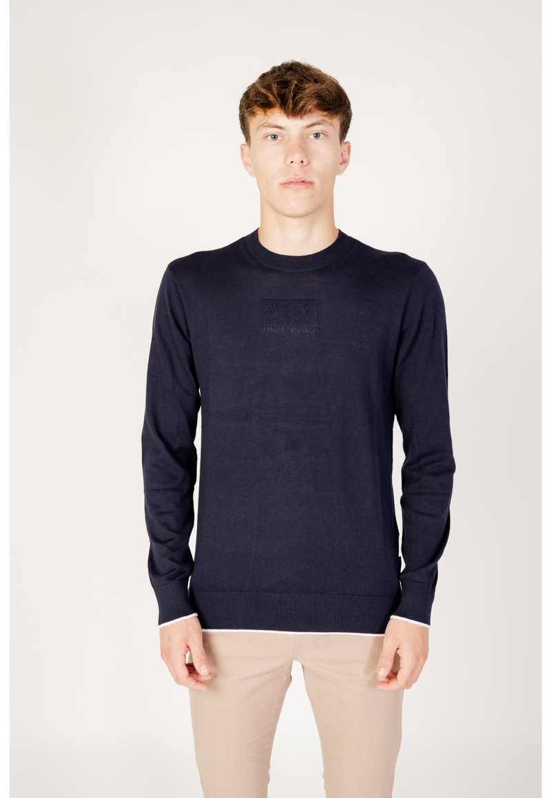 Marineblaue Strickjacke mit langen Ärmeln und Rundhalsausschnitt. Verfügt über ein strukturiertes Logo-Patch auf der Brust und einen kontrastierenden weißen Saum.