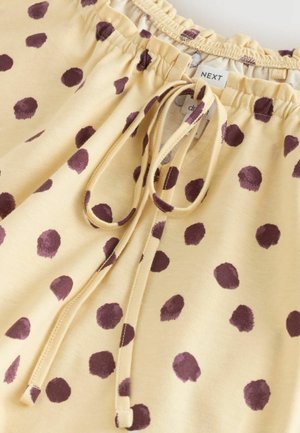 Pantaloni scurți din țesătură galbenă cu buline mov, prevăzuți cu talie elastică adunată, șnur de strângere și textură netedă și moale.