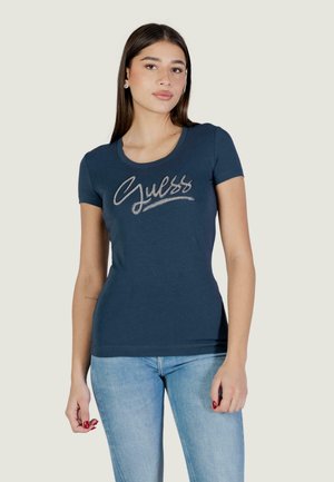 Maglietta blu navy in morbido cotone, con logo "Guess" argentato in corsivo sul petto. Maniche corte, design aderente.