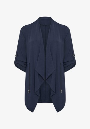 Laivastonsininen avoin neuletakki, jossa on käännetyt hihat, säädettävät nyörit sivuissa ja kapeneva vesiputoushelma.