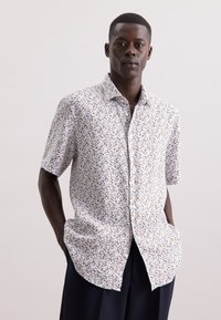 Korte mouwen blouse met knopen van witte stof met een multikleurig bloemenpatroon. Kenmerkt zich door een ontspannen pasvorm en een gebogen zoom.