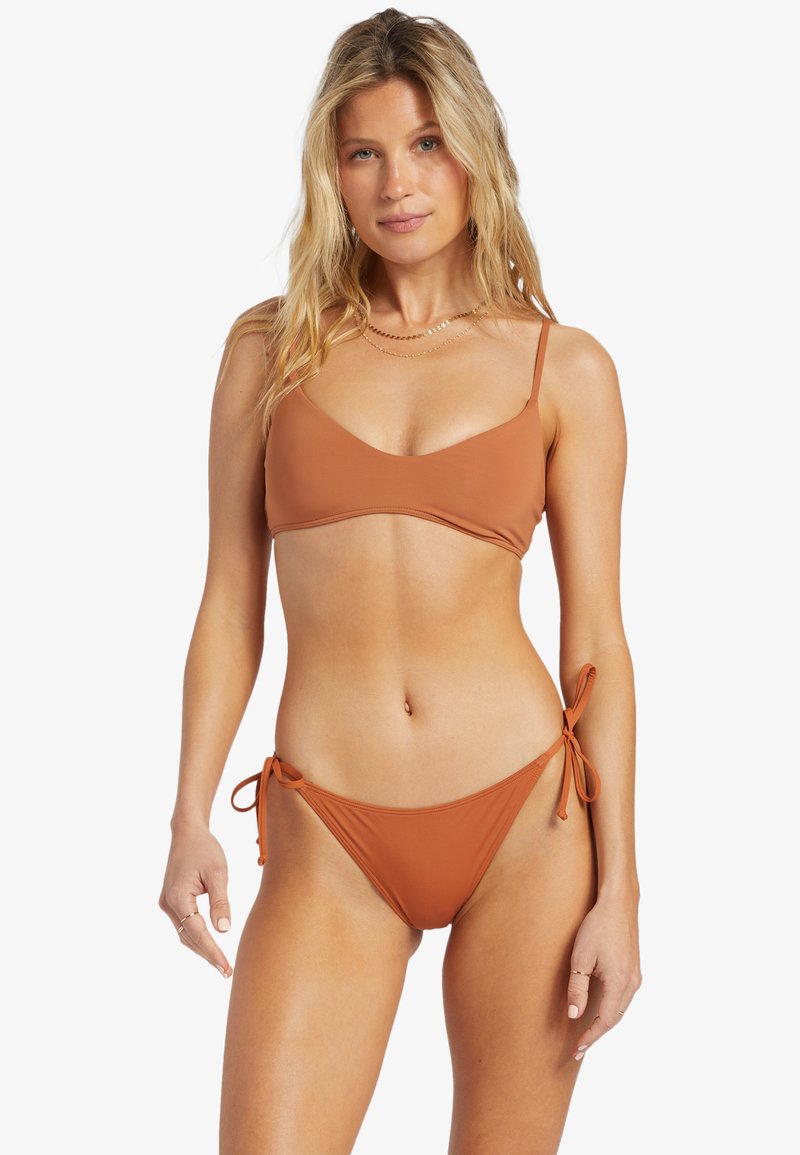 Hnedé bikiny pozostávajúce z braletového vrcholu s nastaviteľnými tenkými ramienkami a nízko strihaných spodných častí s detailmi na viazanie po bokoch. Hladká, elastická látka.
