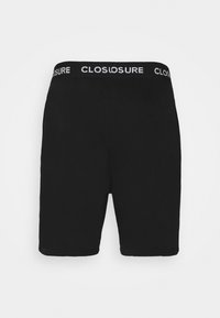 Shorts en coton noirs avec une coupe ajustée. La ceinture élastique arbore le mot "CLOSURE" en blanc. Texture lisse avec un design simple.