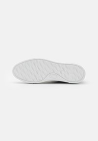 Suola di sneaker bianca con un motivo testurizzato. Presenta una forma arrotondata e bordi lisci, realizzata in gomma per la durata.