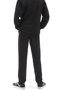 Sudadera y pantalones de chándal negros de mezcla de algodón, con un ajuste relajado. Combinados con zapatillas bajas en negro y blanco.
