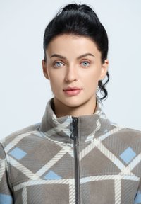 Kurtka polarowa z wysokim kołnierzem, ozdobiona geometrycznym wzorem w odcieniach brązu, jasnego niebieskiego i kremowego, z zapięciem na zamek i miękką teksturą.