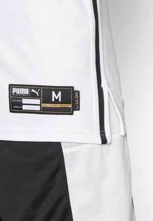 Witte basketbaltrui met zwarte accenten, voorzien van een merklabel, maat M, en een mesh textuur. Gesplitst ontwerp met solide en geperforeerde secties.