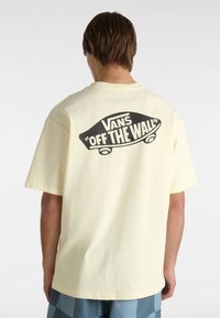 Gelbes Baumwoll-T-Shirt mit kurzen Ärmeln, das auf der Rückseite ein schwarzes "Vans Off The Wall"-Grafikdesign zeigt, mit Rundhalsausschnitt und lockerer Passform.