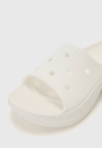 Infradito bianchi realizzati in materiale morbido e testurizzato. Presentano una fascia ampia con fori di ventilazione e una soletta sagomata per il comfort.