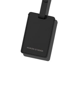 Black leather luggage tag with a stitched edge, featuring a debossed "HORIZN STUDIOS" logo on the front and a loop for attachment.