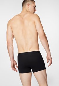Czarne bawełniane bokserki z elastycznym pasem i subtelnym logo. Dopasowany krój o gładkiej fakturze, z wyraźnym, średnim stanem.