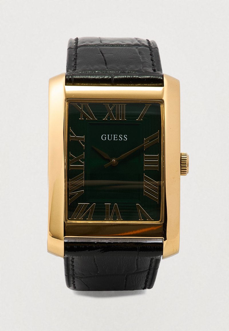 Obdélníkové hodinky Guess s pozlaceným tónem, černým koženým páskem, zeleným ciferníkem a zlatými římskými číslicemi, ukazujícími čas 10:10.