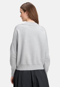 Grauer Strickpullover mit lockerer Passform, überschnittenen Schultern und geripptem Saum. Weicher Griff und minimalistisches Design, von hinten gezeigt.