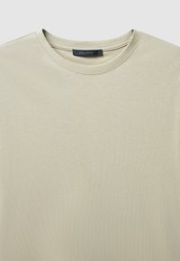 T-shirt beige chiaro realizzato in morbido tessuto testurizzato. Design classico con collo rotondo e minimal cuciture. Etichetta con la scritta "CALLIOPE", taglia L.