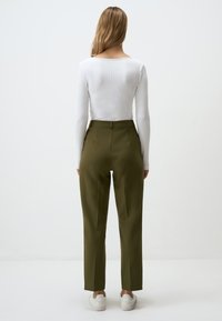 White long-sleeve ribbed top with a square neckline; olive green high-waisted trousers; white sneakers; simple, streamlined silhouette.